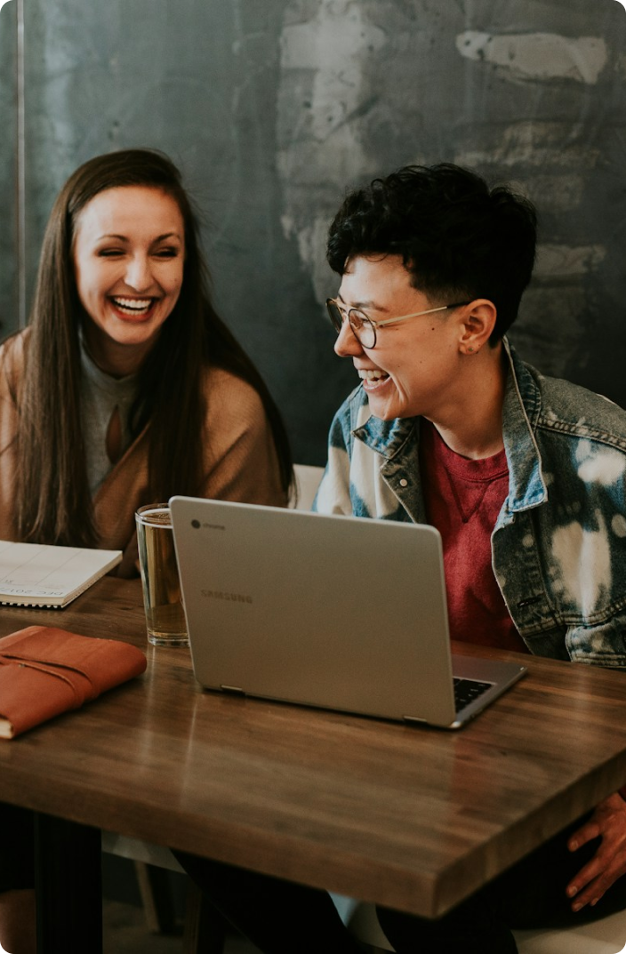 Two colleagues smiling and working on a laptop.